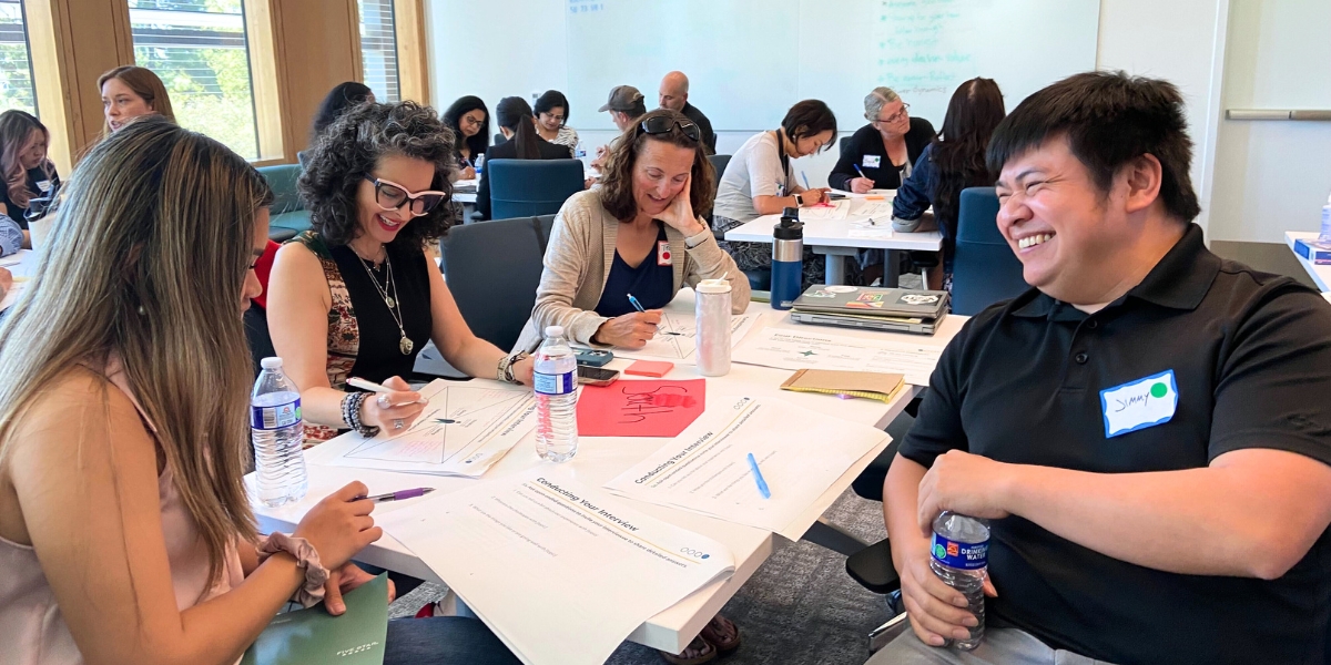 Four participants laughing together while sitting around a table completing a worksheet.