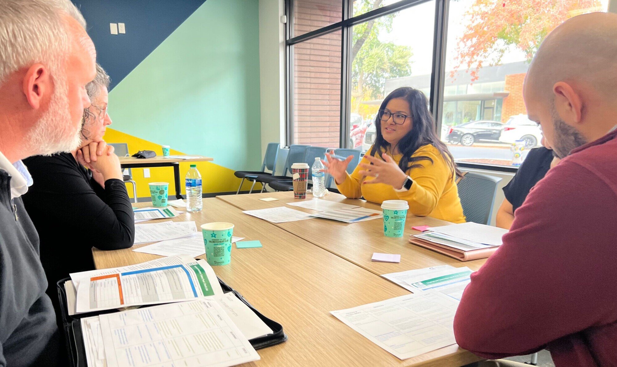 Four people are sitting around a conference table at the Tulare County WIB. In front of them, they each have a printout with descriptions of the Talent Pool Journey.