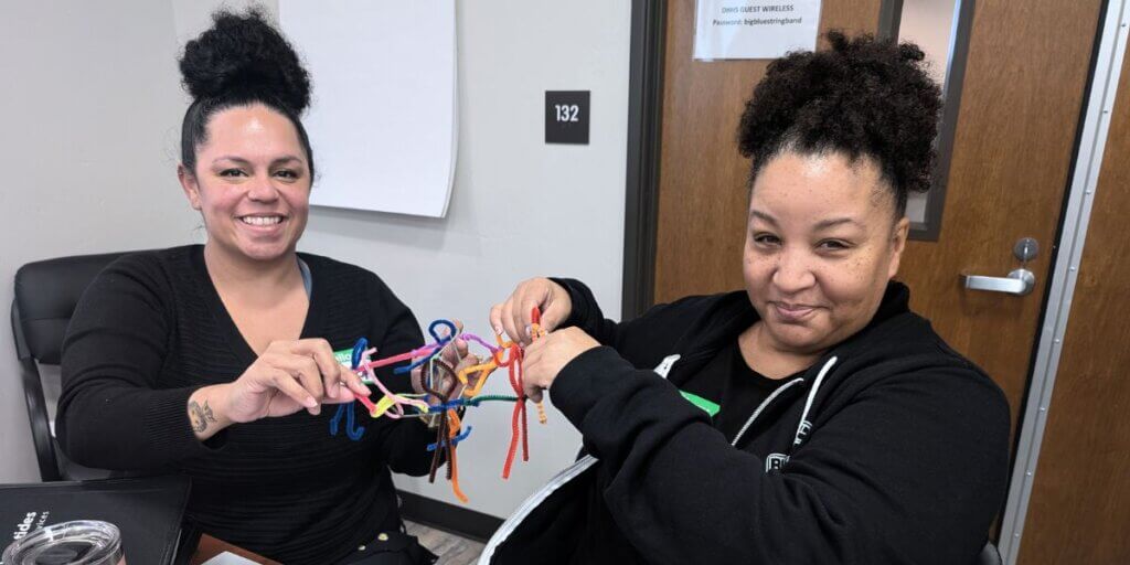 Two attendees holding up the prototype that they built out of pipe-cleaners.