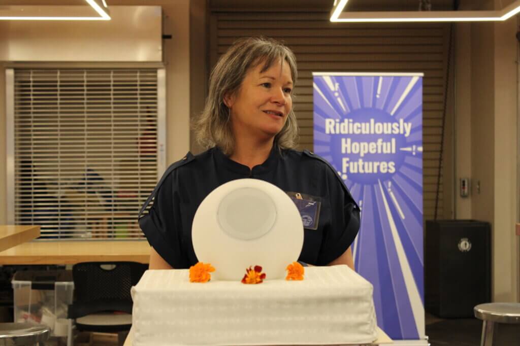picture of a woman standing behind a digital orb speaker