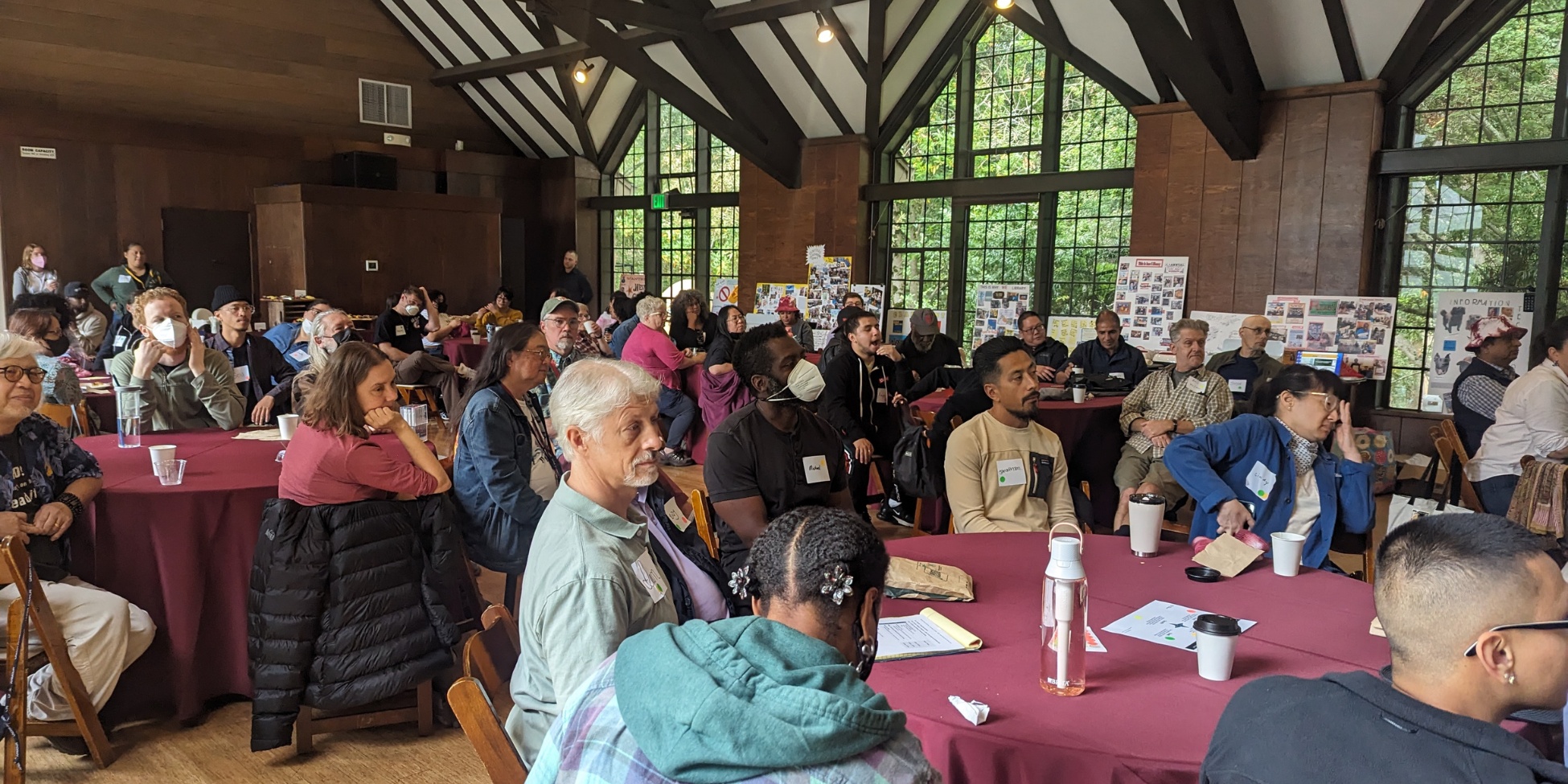 A large room full of people, all arranged in small groups at circular tables.